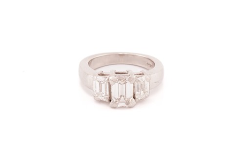 An emerald-cut diamond trilogy ring