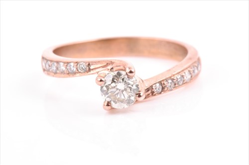 Lot 509 - A rose gold and diamond crossover ring centred...