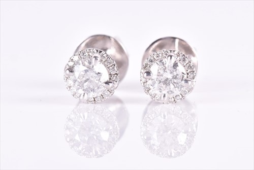 Lot 658 - A pair of white metal and diamond halo...