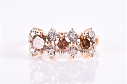 Lot 554 - A white and cognac diamond ring set with three...