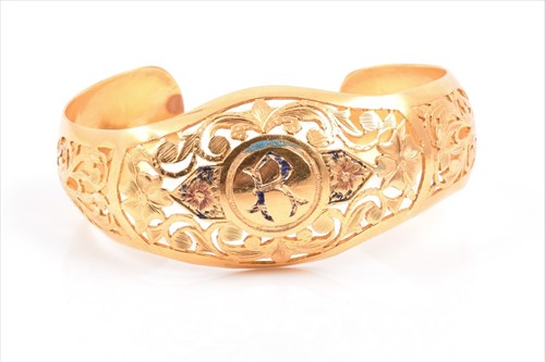 Lot 712 - A yellow metal bangle decorated with an...
