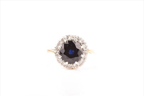 Lot 565 - A diamond and sapphire cluster ring centred...