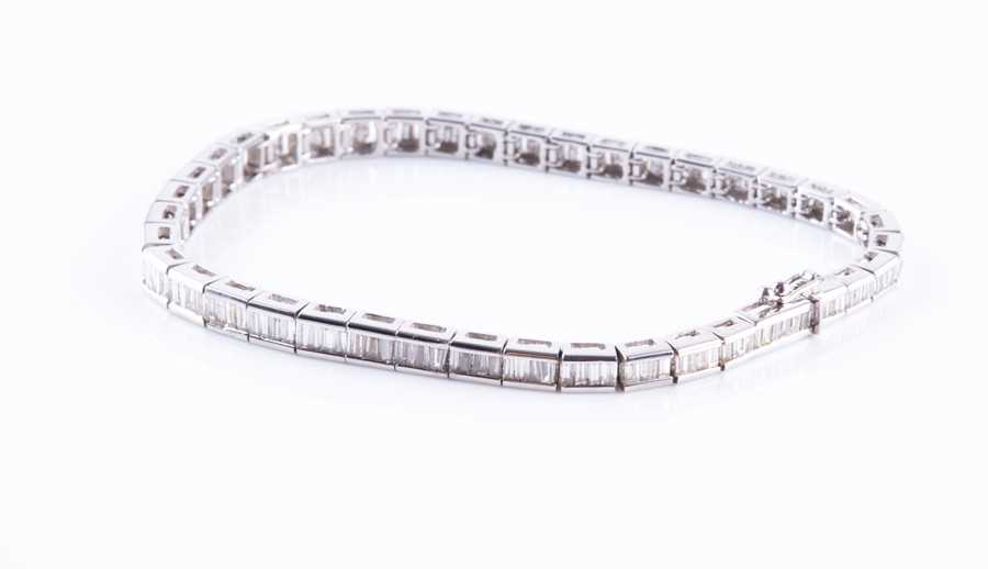 Lot 498 - A diamond line bracelet set with baguette-cut...