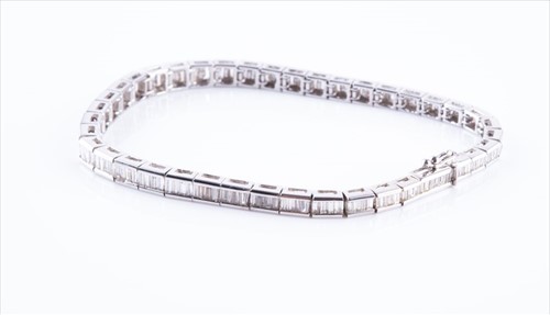 Lot 498 - A diamond line bracelet set with baguette-cut...