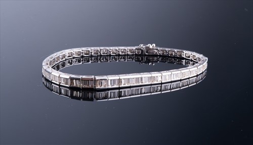 Lot 498 - A diamond line bracelet set with baguette-cut...