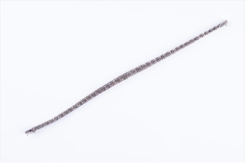 Lot 498 - A diamond line bracelet set with baguette-cut...