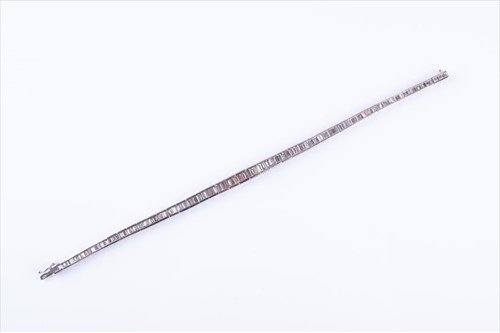 Lot 498 - A diamond line bracelet set with baguette-cut...