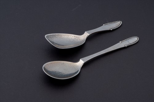 Lot 317 - Two Georg Jensen 'Beaded' whole metal spoons...