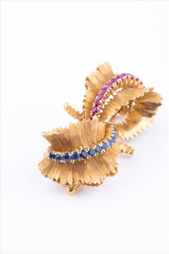 Lot 573 - A sapphire and ruby bow brooch in textured...