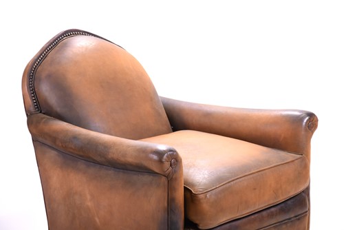 Lot 527 - A tan leather club armchair with padded seat...