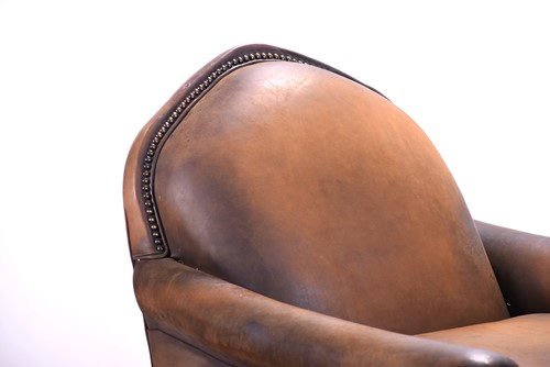 Lot 527 - A tan leather club armchair with padded seat...