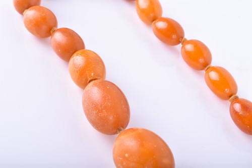 Lot 853 - A butterscotch amber necklace largest bead 2 x...