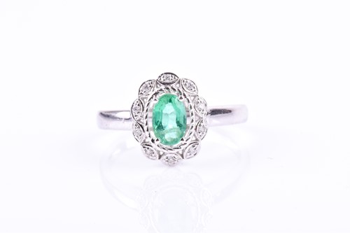 Lot 607 - A 14ct white gold, diamond, and emerald ring...