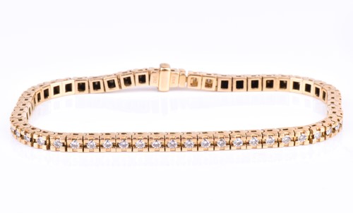 Lot 623 - A yellow gold and diamond line bracelet, set...