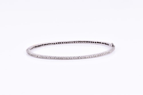 Lot 867 - An 18ct white gold and diamond bangle bracelet,...