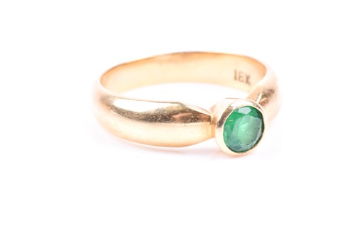 Lot 630 - An 18ct yellow gold and emerald ring, bezel...