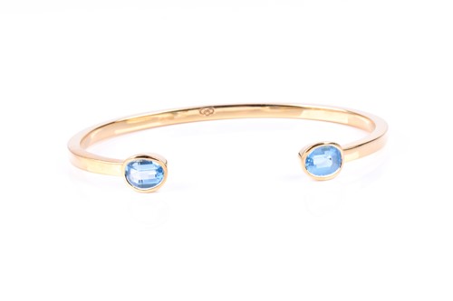 Lot 503 - An 18ct gold and blue topaz torque bracelet,...