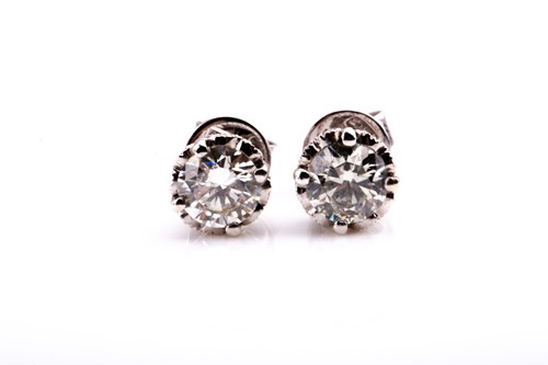Lot 547 - A pair of solitaire diamond ear studs, set...
