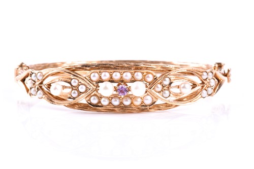 Lot 822 - A yellow metal, amethyst, and pearl bangle,...