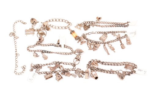 Lot 887 - A group of six various silver charm bracelets,...