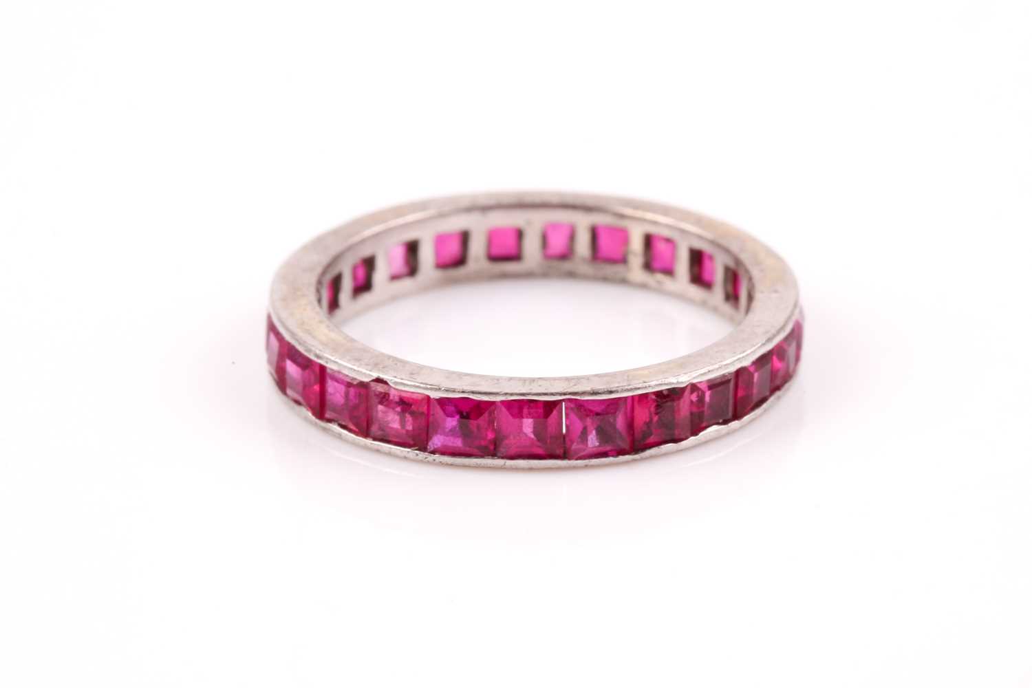 Lot 45 - A white metal and ruby eternity ring,...