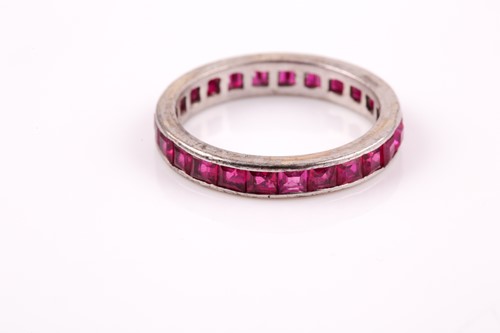 Lot 45 - A white metal and ruby eternity ring,...