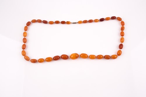 Lot 155 - A butterscotch amber beaded necklace, the...