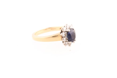 Lot 154 - A sapphire and diamond cluster ring; the oval...