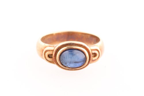 Lot 329 - A yellow metal and cabochon sapphire ring, the...
