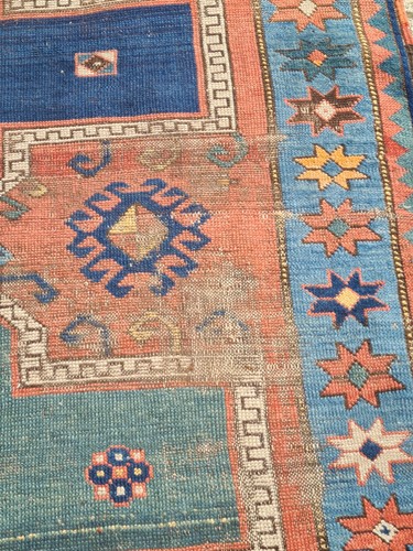 Lot 380 - An old red gound Kazak rug. With three hooked...