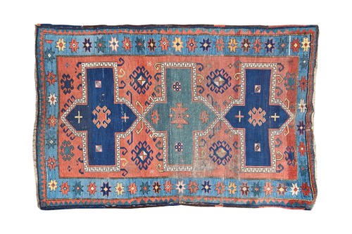 Lot 380 - An old red gound Kazak rug. With three hooked...