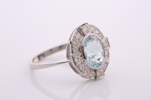 Lot 90 - An aquamarine and diamond oval cluster ring in...