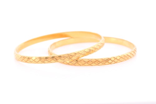 Lot 167 - A pair of Indian yellow metal bangles, with...