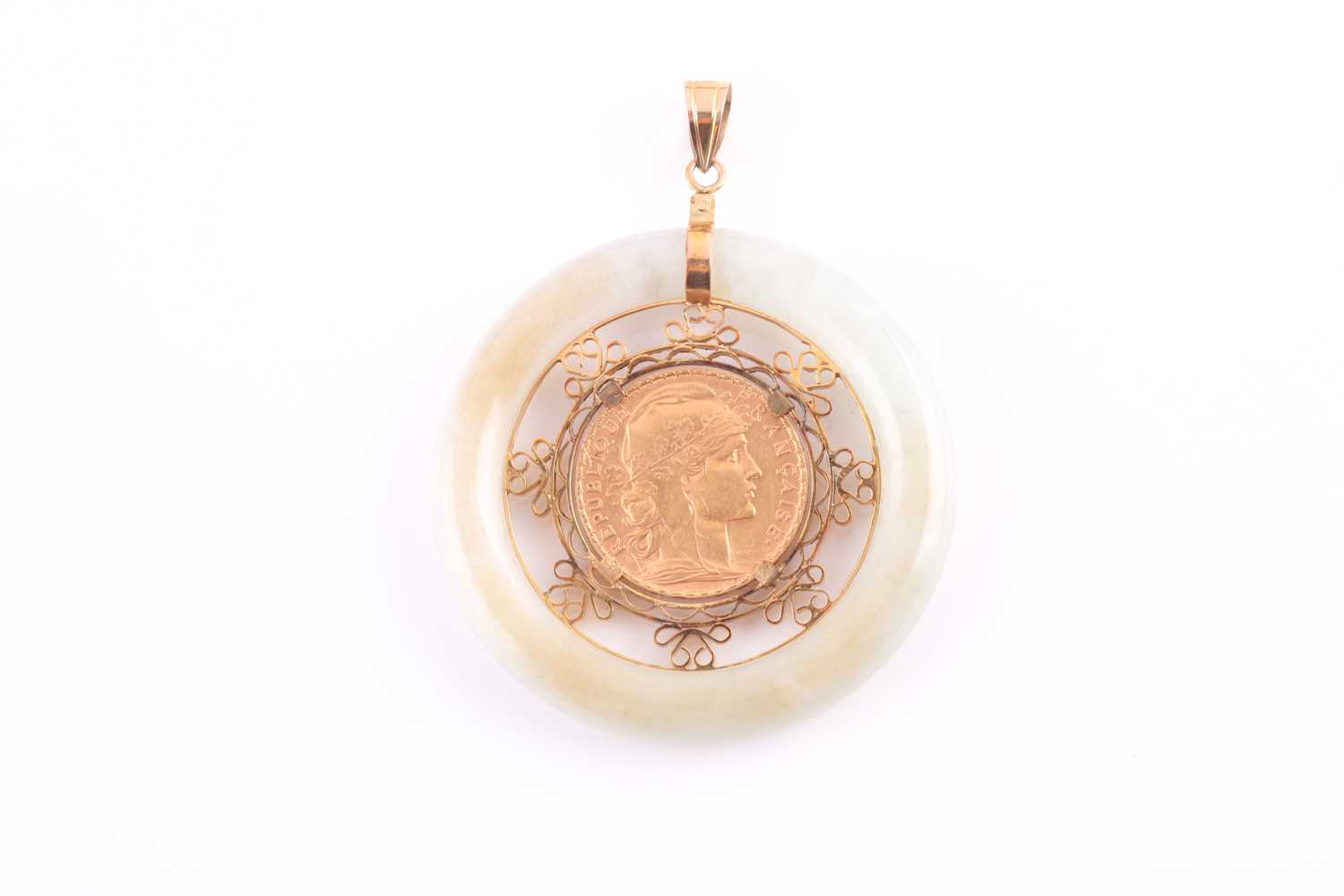 Lot 104 - A yellow metal and jade pendant, the pale...