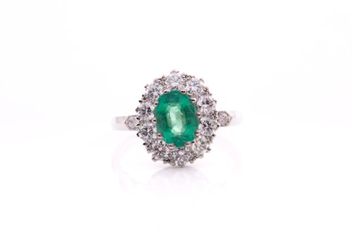 Lot 21 - A platinum, diamond, and emerald cluster ring,...