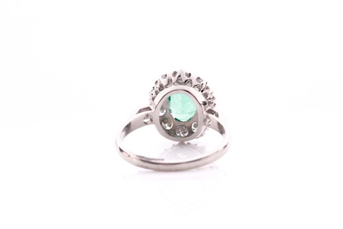Lot 21 - A platinum, diamond, and emerald cluster ring,...