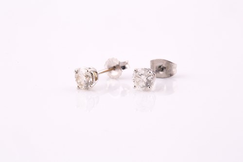 Lot 75 - A pair of single stone diamond earrings; the...