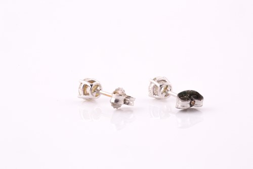 Lot 75 - A pair of single stone diamond earrings; the...