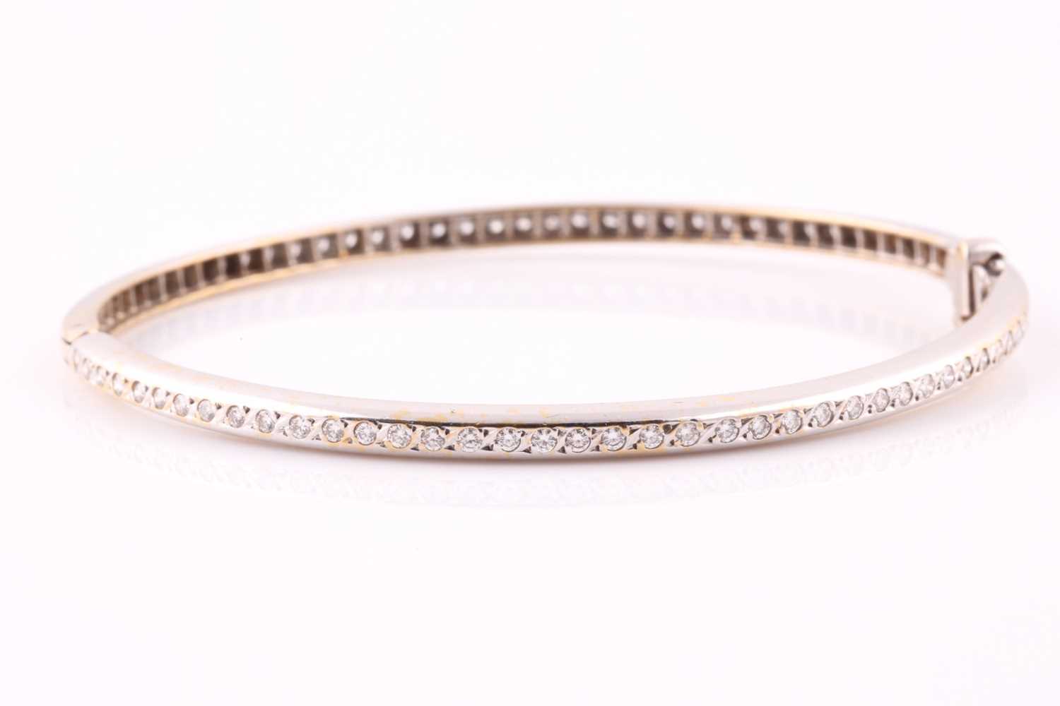 Lot 242 - A diamond bangle; set with a line of round...