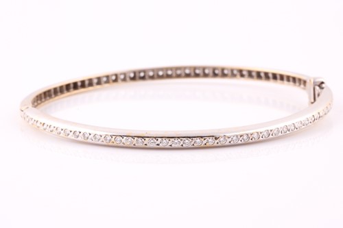 Lot 242 - A diamond bangle; set with a line of round...
