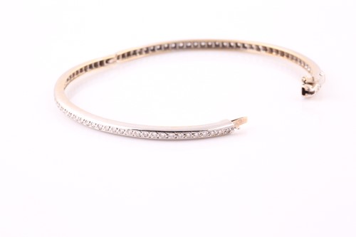 Lot 242 - A diamond bangle; set with a line of round...