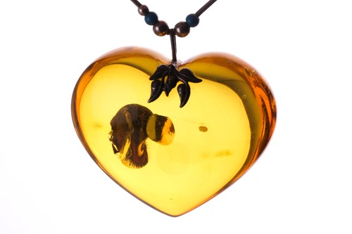 Lot 194 - A large heart shaped copal resin pendant, on a...