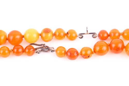Lot 231 - A double-strand amber necklace, each...
