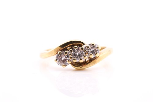 Lot 579 - A three stone diamond crossover ring; the...