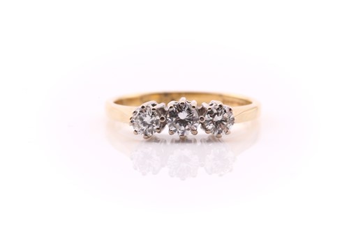 Lot 772 - A three stone diamond half hoop ring; the...