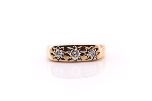 Lot 565 - A three stone gypsy set diamond ring; the...