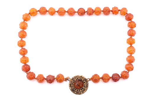 Lot 46 - A single row carved amber bead necklace, each...