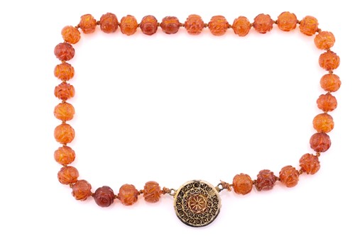 Lot 46 - A single row carved amber bead necklace, each...