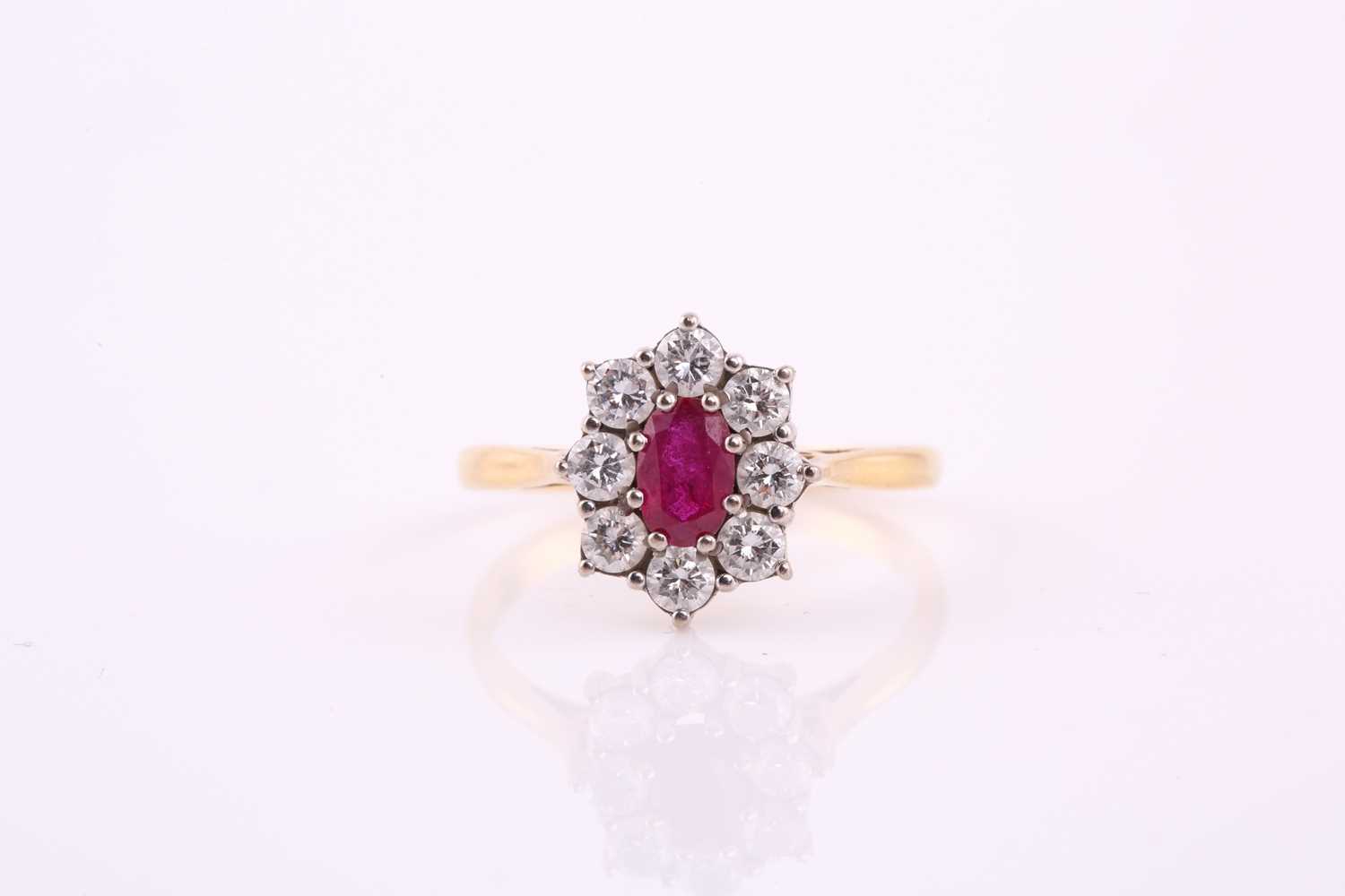 Lot 79 - A ruby and diamond cluster ring; the oval cut...