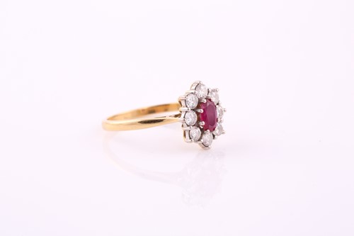 Lot 79 - A ruby and diamond cluster ring; the oval cut...